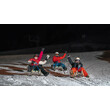 Drei Rodler:innen fahren bei Nacht mit Stirnlampen eine beleuchtete Rodelbahn hinab / Three tobogganers ride down a lit toboggan run at night with headlamps