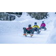 Rodler:innen fahren auf einer schmalen, verschneiten Bahn zwischen hohen Schneewänden / Sledders descend a narrow, snowy track flanked by high snowbanks