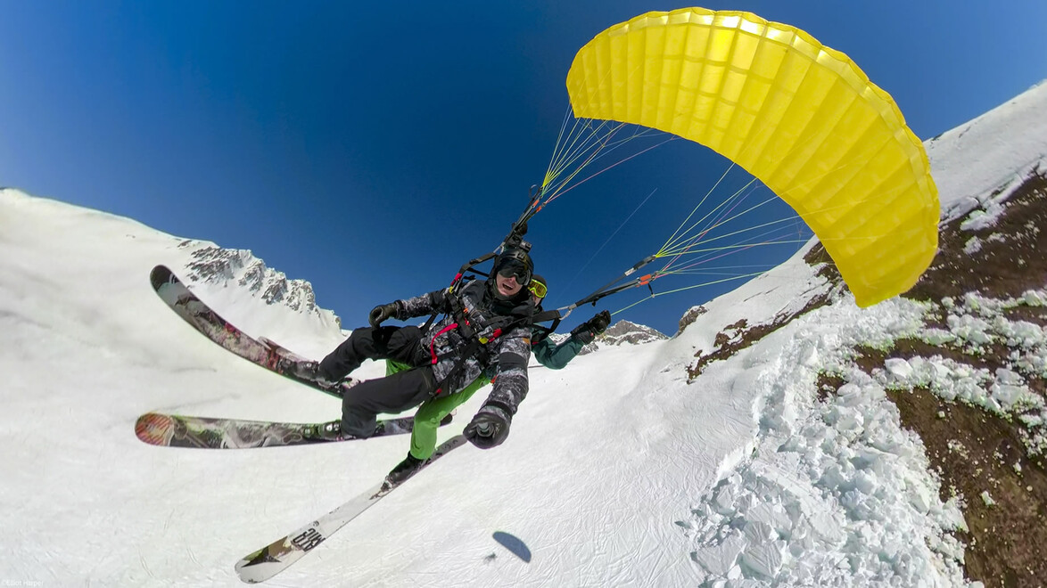 Tandem-Paragleiten mit gelbem Schirm über Pisten im Winter / Tandem paragliding with yellow canopy above ski slopes in winter
