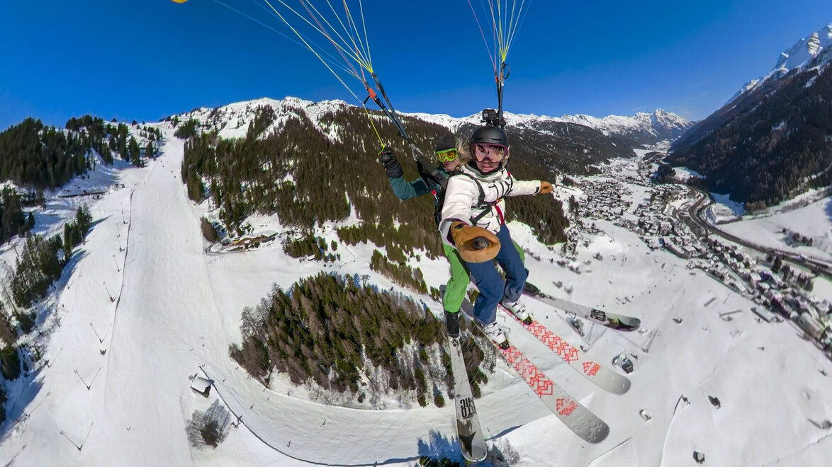 Tandemflug mit Skiern über dem Tal bei sonnigem Wetter / Tandem flight with skis above valley in sunny weather