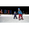 Eislaufen am Abend / Ice skating in the evening Zwei Kinder laufen am beleuchteten Eislaufplatz bei Nacht / Two children skating at night on lit ice rink