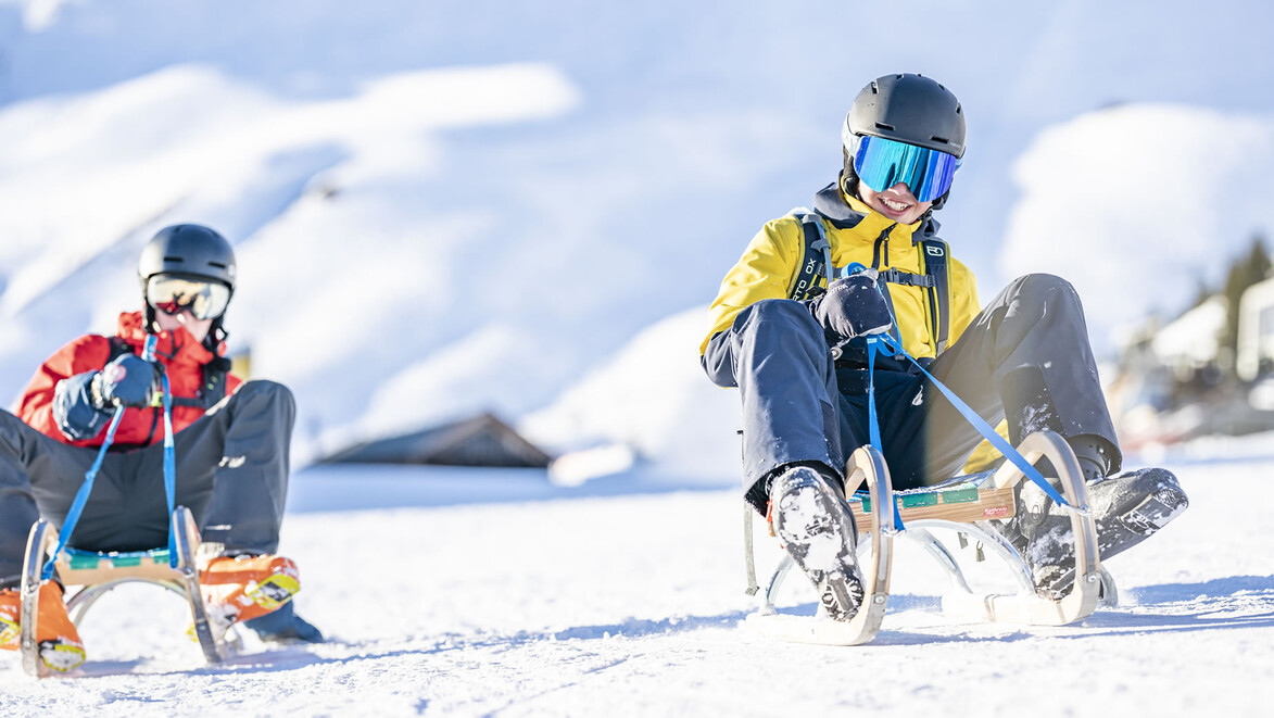 Rodelspaß für Kinder / Toboggan fun for kids Zwei Kinder auf Rodeln fahren rasant den Hang hinunter / Two children speed downhill on sleds