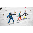 Skischule für Kinder / Ski school for kids Skilehrerin mit zwei Kindern beim Pflugfahren auf Übungshang / Ski instructor with two children snowploughing on practice slope