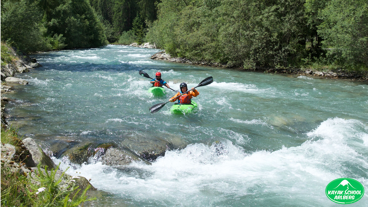 Zwei Kajakfahrer manövrieren durch einen schnell fließenden Wildbach / Two kayakers maneuvering through a fast-flowing stream