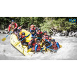 Eine Gruppe Menschen beim Wildwasser-Rafting in einem gelben Schlauchboot auf einem spritzenden Fluss / A group of people whitewater rafting in a yellow inflatable boat on a splashing river