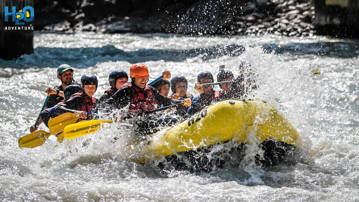 Raftinggruppe fährt durch starke Stromschnellen mit spritzendem Wasser / Rafting group going through strong rapids with splashing water