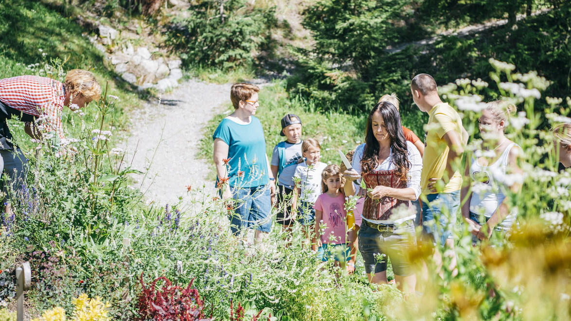 Gruppe aus Erwachsenen und Kindern bei geführter Kräuterwanderung im Garten / Group of adults and children on a guided herb tour in a garden