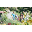 Gruppe aus Erwachsenen und Kindern bei geführter Kräuterwanderung im Garten / Group of adults and children on a guided herb tour in a garden