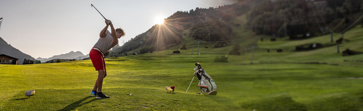 Golfer teeing off in St. Anton am Arlberg, with a stunning backdrop at dusk