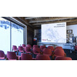 Konferenzraum mit roten Stühlen, Leinwand und Panoramablick auf verschneite Landschaft / Conference room with red chairs, screen and panoramic view of snowy landscape