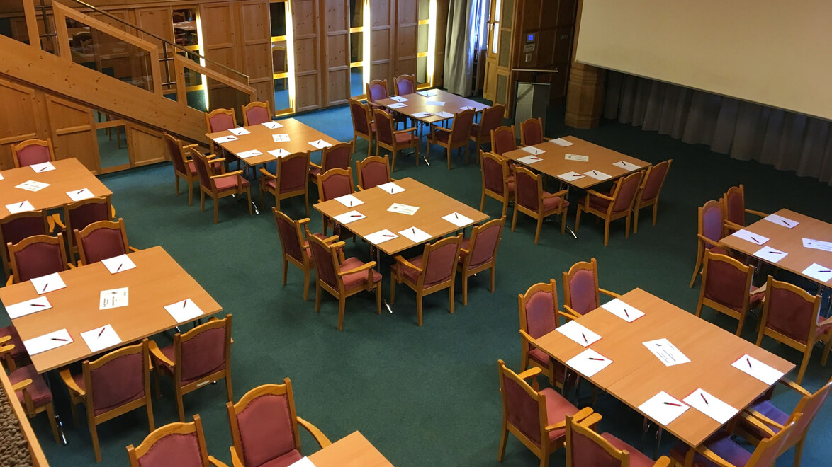 Konferenzraum mit mehreren Gruppentischen und Stühlen in ruhiger Atmosphäre / Conference room with multiple group tables and chairs in calm setting