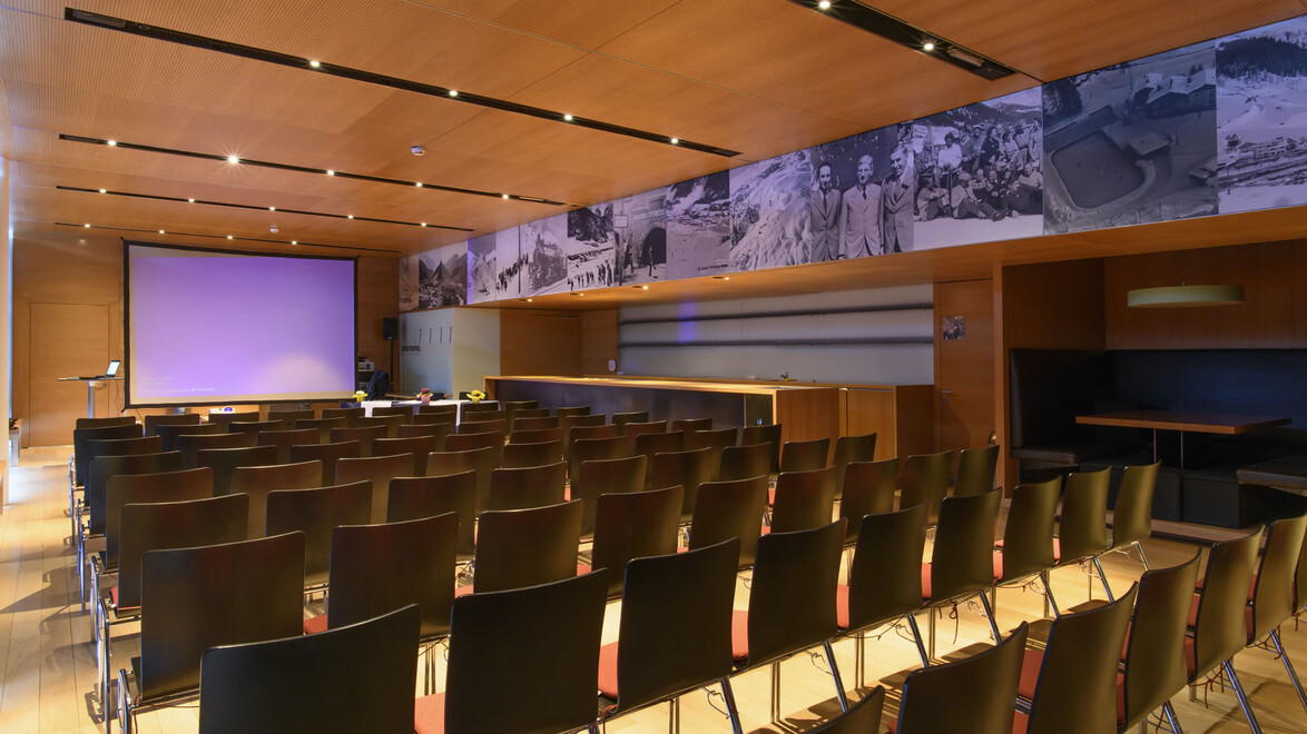 Holzvertäfelter Konferenzsaal mit Bestuhlung und Projektionsfläche / Wood-paneled conference room with seating and projection screen