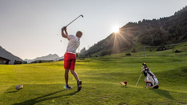 Golfer teeing off in St. Anton am Arlberg, with a stunning backdrop at dawn
