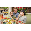 Ein Vater isst mit zwei Kindern an einem Tisch im Freien eine herzhafte Mahlzeit / A father shares a hearty meal with two children at an outdoor table