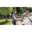 Eine Mutter unterstützt ihr Kind beim Klettern an einer geneigten Boulderwand im Waldspielplatz / A mother helps her child climb a tilted bouldering wall at a forest playground
