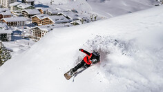 Snowboarder rides steep powder slopes above the village St. Christoph am Arlberg.