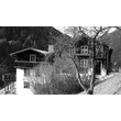 Altes Holzhaus mit Balkon und Baum im Vordergrund, Hanglage / Old wooden house with balcony and tree in front, hillside location