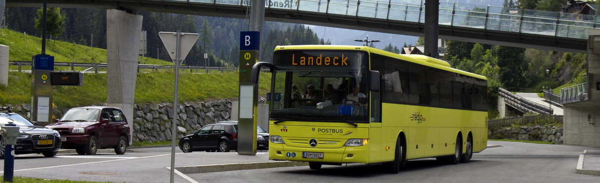 Gelber „Postbus“ bei der Abfahrt vom Terminal West mit der Rendlbahn im Hintergrund