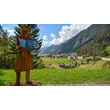Eine rostfarbene Figur mit Buch steht vor dem Panorama von Schnann im Stanzertal / A rust-colored figure with an open book stands in front of the Schnann valley panorama