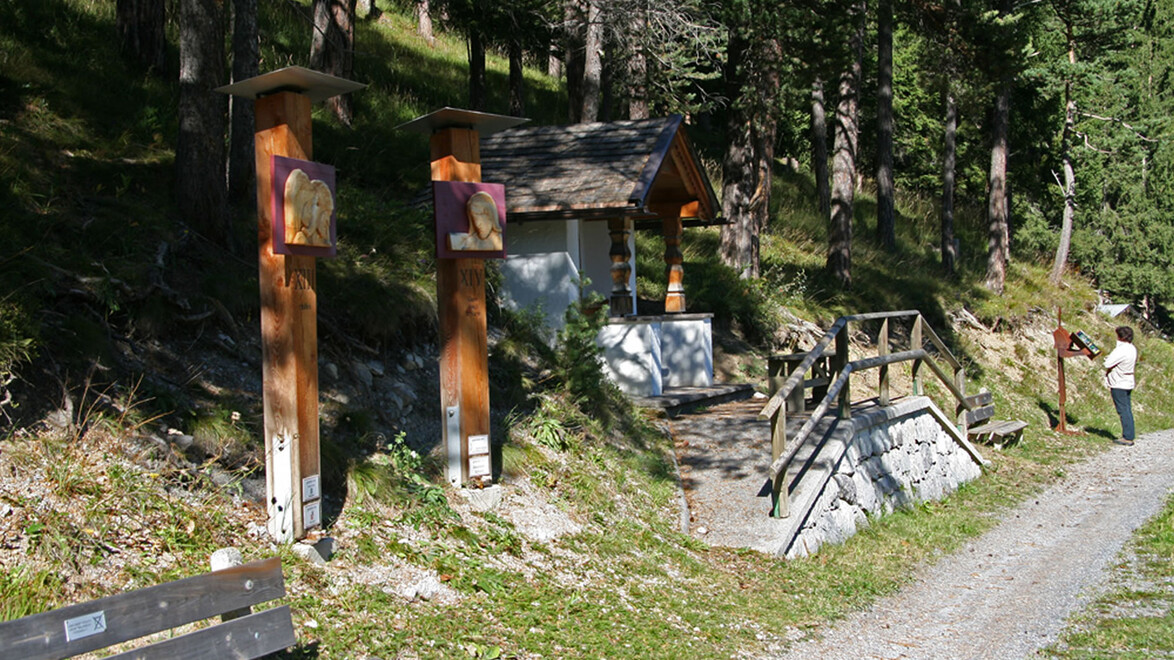 Infotafeln und geschnitzte Holzfiguren am Waldrand entlang des Themenwegs / Info boards and carved wooden figures at the forest edge along the themed trail