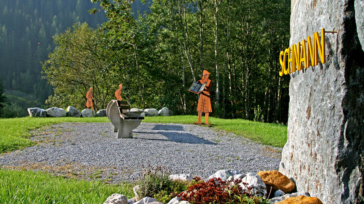 Sitzbänke und Figuren auf einem Rastplatz beim Ortseingang von Schnann / Benches and figures at a rest area near the entrance to Schnann