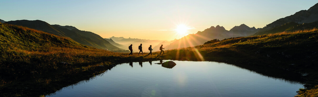 Wanderer an einem Bergsee bei Sonnnenuntergang in St. Anton am Arlberg