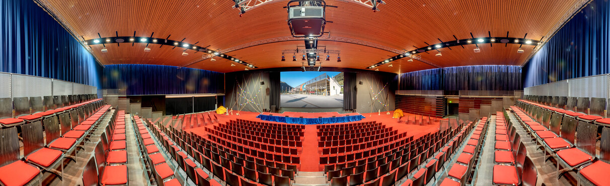 Weitwinkelaufnahme von der WM-Halle im Arlberg WellCom in St. Anton am Arlberg. Aufgebaut ist eine Tribüne mit Sitzplätze sowie eine Bühne mit Leinwand
