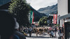 Eine Herde Kühe zieht durch das Dorfzentrum von St. Anton, eingerahmt von Bergen und Zuschauern. / A herd of cows moves through the village center of St. Anton, surrounded by mountains and spectators.