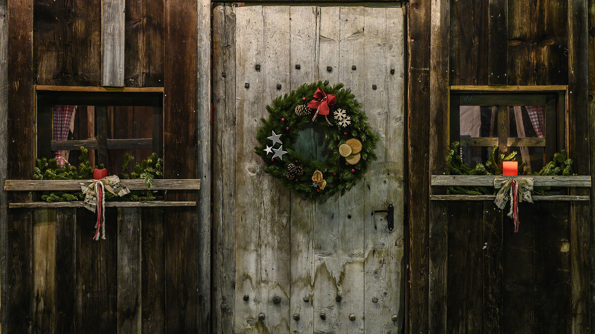 Alte Holztür mit rundem Adventkranz und dekorierten Fenstern / Old wooden door with circular Christmas wreath and decorated windows