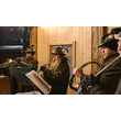 Bläsergruppe mit traditionellen Hüten spielt in weihnachtlich beleuchtetem Holzstand / Brass band in traditional hats plays in a Christmas-lit wooden stall