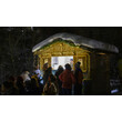 Besucher:innen stehen an beleuchtetem Verkaufsstand mit Lichterkette im Schnee / Visitors at illuminated market stall with fairy lights in the snow