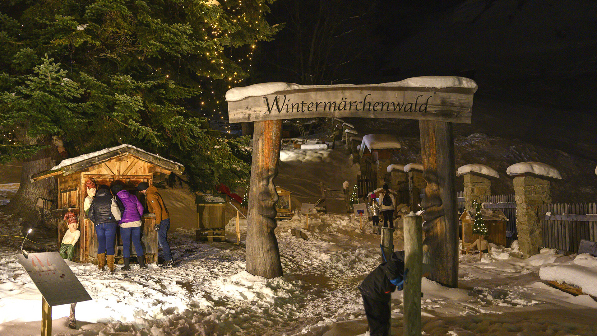 dventweg mit Krippe / Christmas trail with nativity scene ChatGPT fragen Adventweg mit Krippe, Holzportal und Besuchern im Schnee bei Nacht / Advent path with nativity scene, wooden gate and visitors in the snow at night