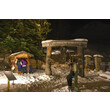 Adventweg mit Krippe, Holzportal und Besuchern im Schnee bei Nacht / Advent path with nativity scene, wooden gate and visitors in the snow at night