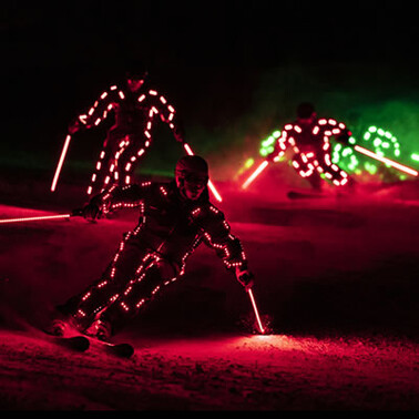 Skiers in glowing LED suits race through the snow at night. The spectacular ski show in St. Anton am Arlberg fascinates with lights, motion, and action.