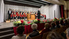 Blick auf das Publikum und den Chor auf der Bühne mit Weihnachtsdekorationen im Vordergrund / View of the audience and choir on stage with Christmas decorations in the foreground