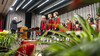 Ein Chor in roten Uniformen steht auf einer Bühne, vor ihnen ein Dirigent und ein weihnachtlich geschmückter Konzertsaal / A choir in red uniforms stands on stage, in front a conductor and a festively decorated concert hall