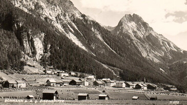 Schwarzweißaufnahme von Schnann mit Blick auf die imposante Eisenspitze – Tiroler Dorfidylle um 1900.