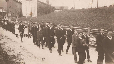 Schwarz-weiß Foto der Schnanner Dorfgemeinschaft bei einer feierlichen Prozession um 1900.