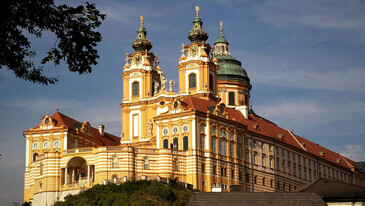 Stift Melk ein großes barockes Kloster mit zwei Türmen und Kuppel, gelb-orange gestrichen.