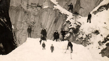 Mehrere Personen stehen und sitzen im Schnee vor in der Schnanner Klamm. Ein Mann trägt Skier.