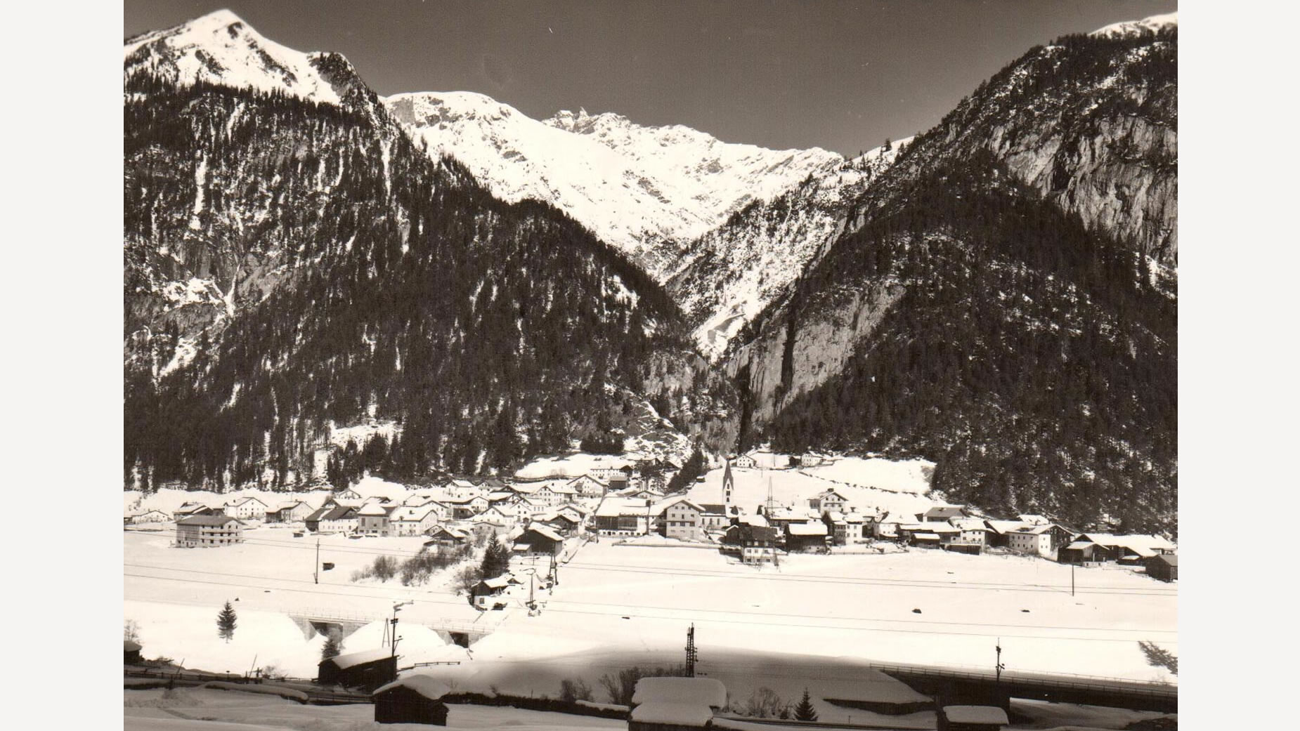 Winterliche Gesamtansicht von Schnann mit verschneiten Dächern und umgebenden Bergen / Winter view of Schnann with snow-covered roofs and surrounding mountains