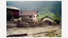 Schlammlawine überzieht einen Bauernhof in Hanglage, Gebäude und Gelände mit Geröll bedeckt / Mudslide covers hillside farm, buildings and ground with debris