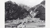 Historische Schwarzweißaufnahme eines Dorfes im Tal zwischen bewaldeten Bergen / Historic black-and-white photo of village in valley between forested mountains