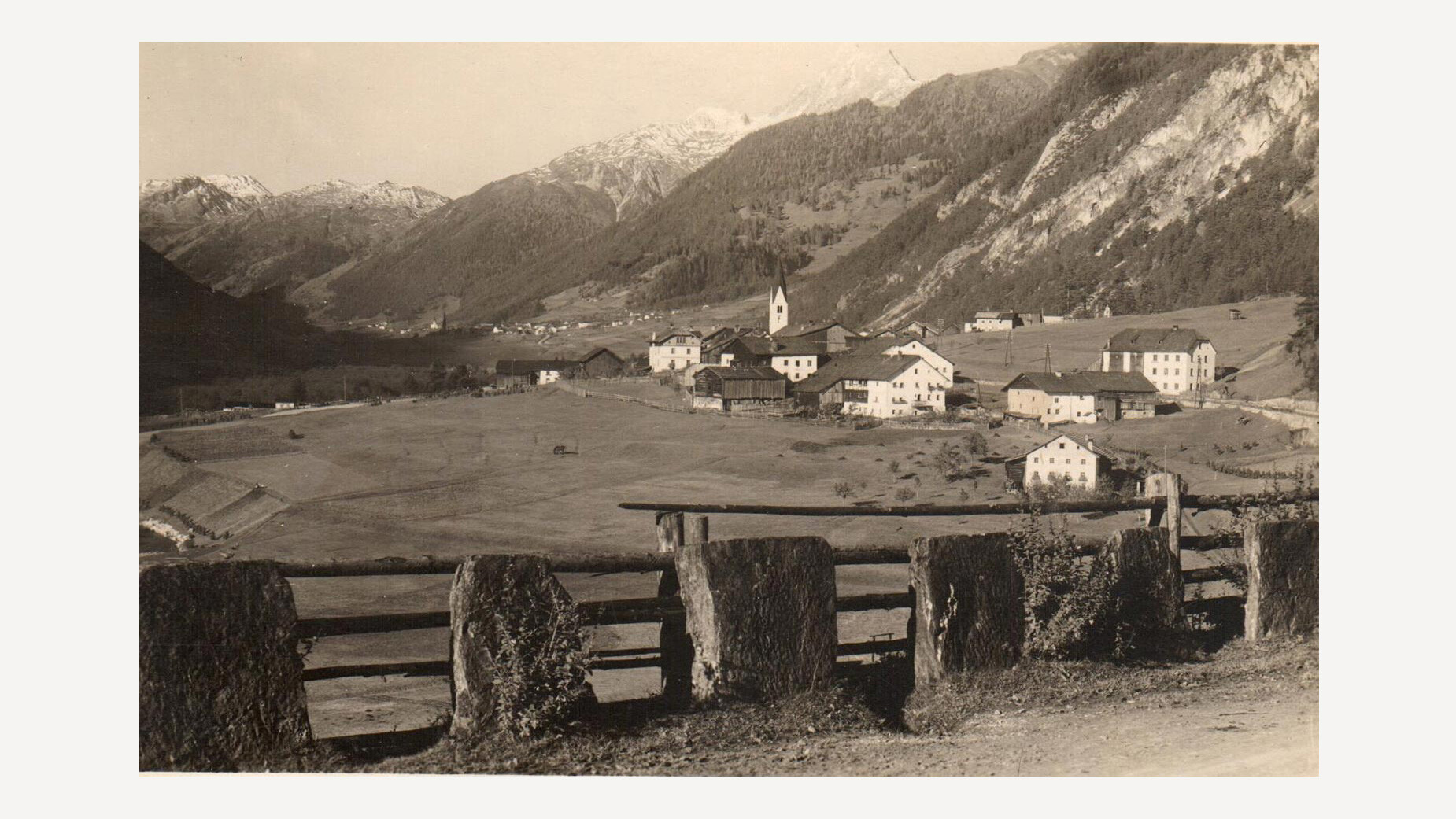Historisches Dorfbild von Schnann mit landwirtschaftlichen Gebäuden und Bergen im Hintergrund, gut sichtbare Heuschober im Vordergrund / Historic village scene of Schnann with agricultural buildings and mountains in the background, visible hay barns in the foreground