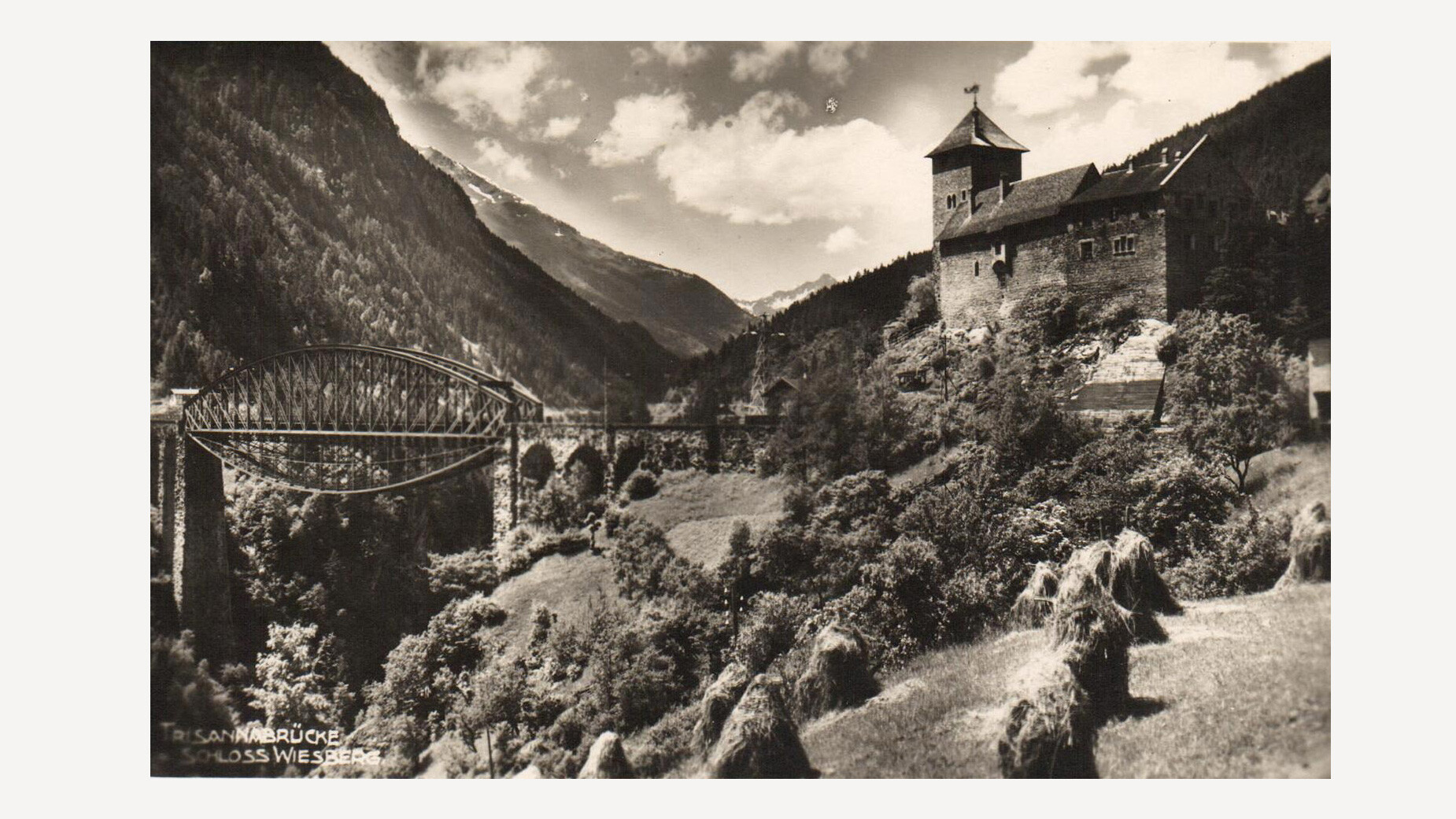 Postkartenmotiv der Trisannabrücke mit Schloss Wiesberg im Hintergrund, eingebettet in das Paznauntal / Postcard image of the Trisanna Bridge with Wiesberg Castle in the background, nestled in the Paznaun Valley