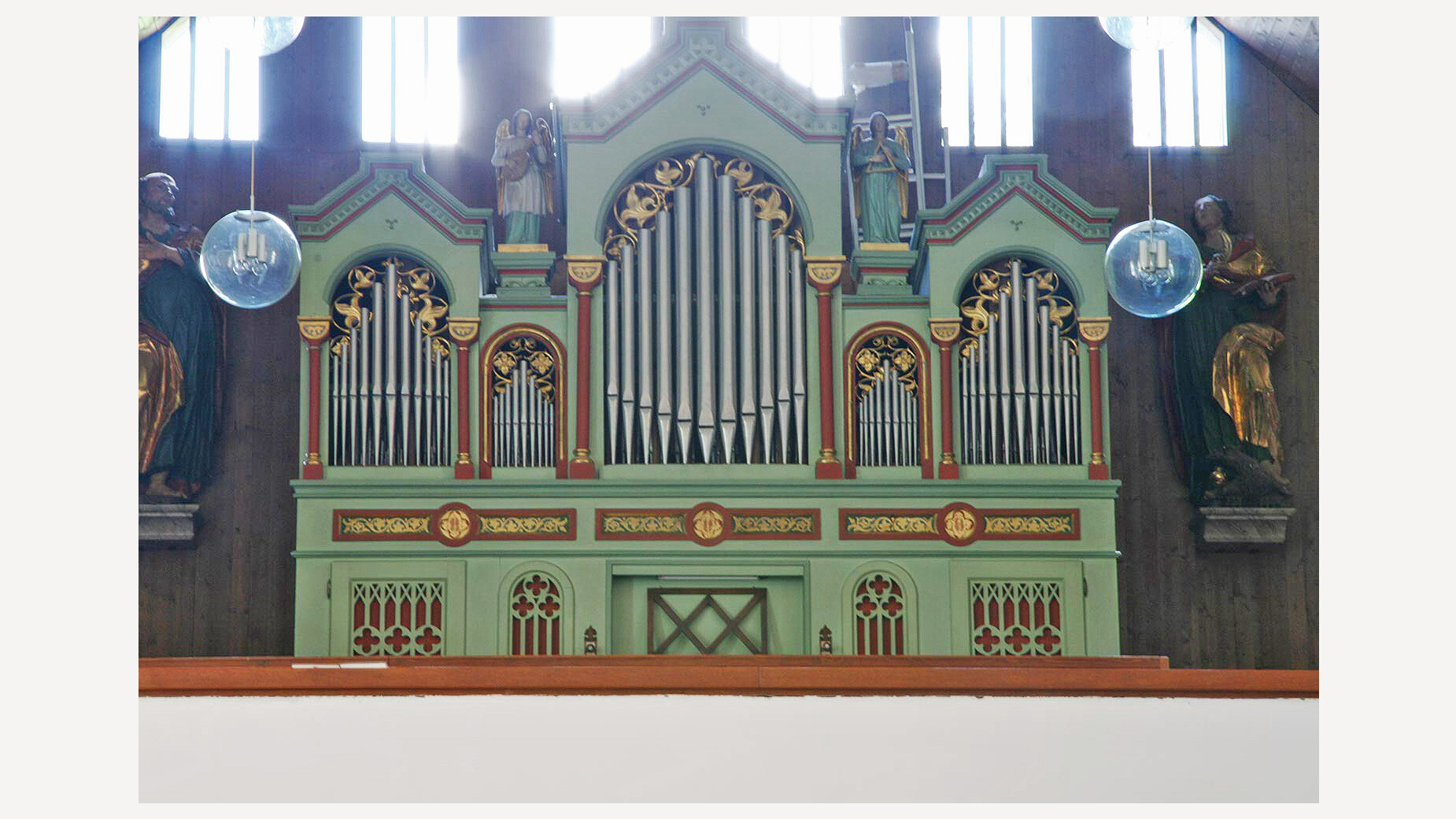Grüne Kirchenorgel mit goldenen Verzierungen in modernem Kirchenraum / Green church organ with golden decorations in a modern church space