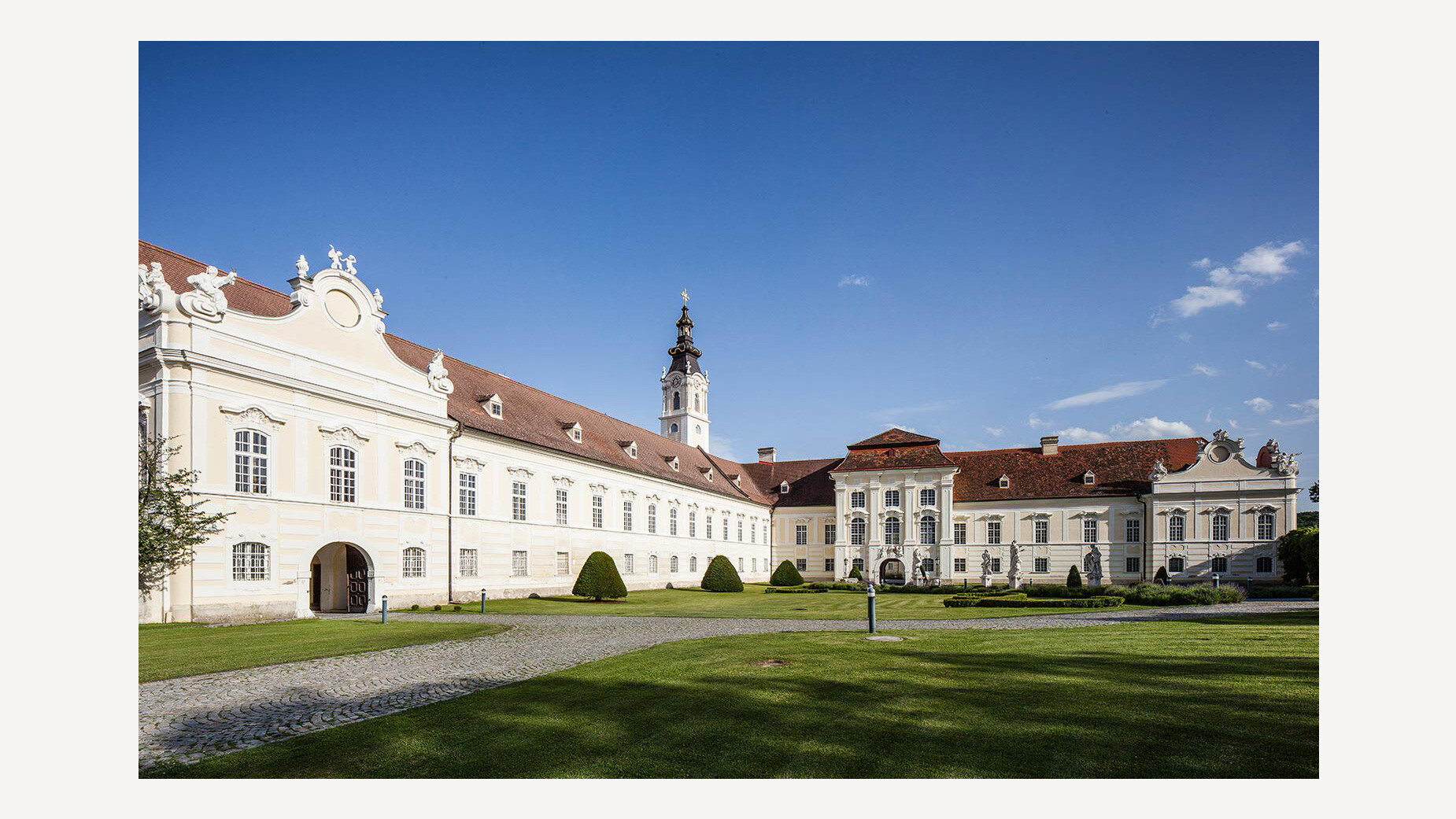 Barocke Klosteranlage mit weißer Fassade und gepflegtem Garten im Vordergrund / Baroque monastery complex with white façade and well-kept garden in the foreground