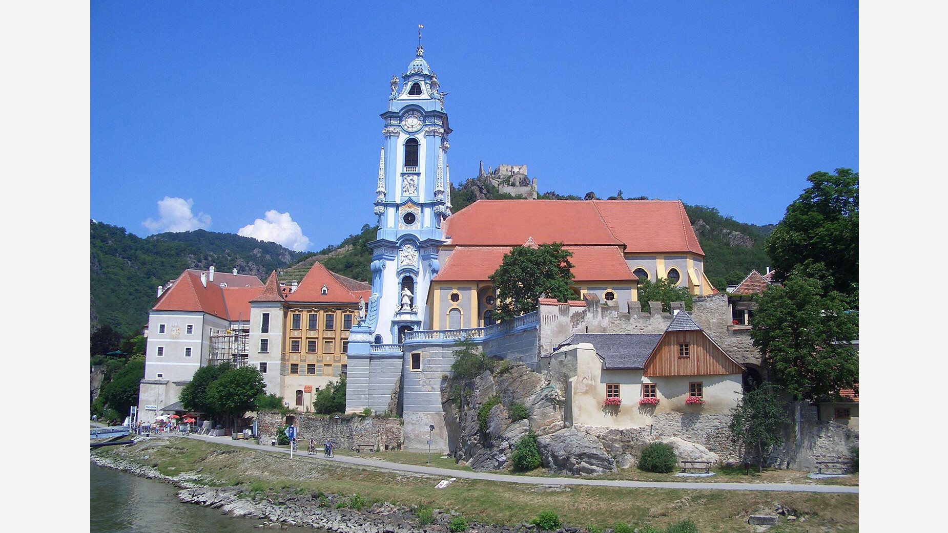 Stift Dürnstein in der Wachau / Dürnstein Abbey in the Wachau Barockkirche mit blauem Turm am Donauufer inmitten historischer Gebäude / Baroque church with blue tower on the Danube riverbank surrounded by historic buildings