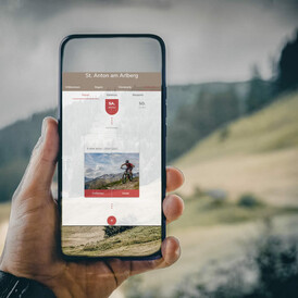 Ein Smartphone mit der PIA geöffnet vor sommerlichen Hängen