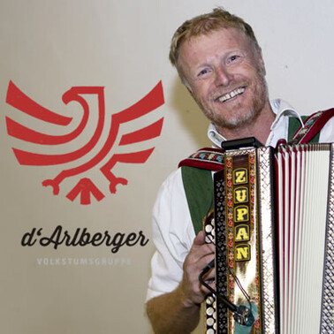 A folk musician plays the accordion with the group d'Arlberger in traditional dress.